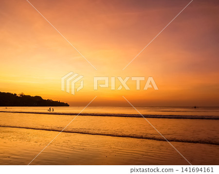 Sunset over Jimbaran Beach with silhouetted figures on shoreline, Bali, Indonesia Sunset over Jimbaran Beach with silhouetted figures on shoreline, Bali, Indonesia 141694161