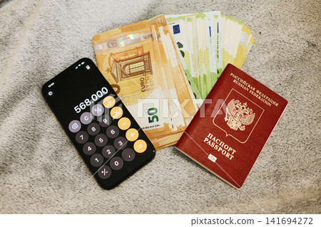 Russian passport, euro banknotes and calculator are arranged on a soft surface. Concept of relocation from Russia, migration costs and financial planning for moving abroad Russian passport, euro banknotes and calculator are arranged on a soft surface. Concept of relocation from Russia, migration costs and financial planning for moving abroad 141694272
