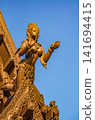 Carved wooden deity statue on rooftop against blue sky at Sanctuary of Truth, Pattaya 141694415