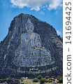 Golden outline Buddha image carved on cliff face with Thai flags at summit in Khao Chee Chan Pattaya Thailand 141694425
