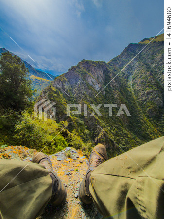 POV Hiker Sitting on Cliff Edge Overlooking Mountain Landscape POV Hiker Sitting on Cliff Edge Overlooking Mountain Landscape 141694680