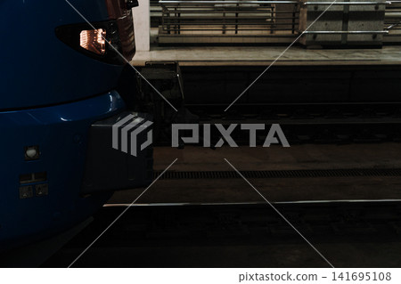 Blue passenger train stands at underground railway platform in low light. Concept of urban transportation, mobility and modern transit Blue passenger train stands at underground railway platform in low light. Concept of urban transportation, mobility and modern transit 141695108