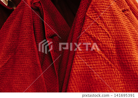 Red textured bathroom towels hanging in warm indoor lighting inside a home furnishing store. Cozy hygiene and comfort concept Red textured bathroom towels hanging in warm indoor lighting inside a home furnishing store. Cozy hygiene and comfort concept 141695391
