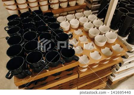 Black and white ceramic cups arranged on shelves in a modern home goods store. Minimal kitchenware concept for cafe and interior lifestyle themes Black and white ceramic cups arranged on shelves in a modern home goods store. Minimal kitchenware concept for cafe and interior lifestyle themes 141695440