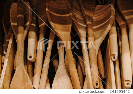 Assorted wooden spatulas and cooking utensils displayed in a home goods store. Natural kitchen accessory concept with rustic lifestyle aesthetics 141695441