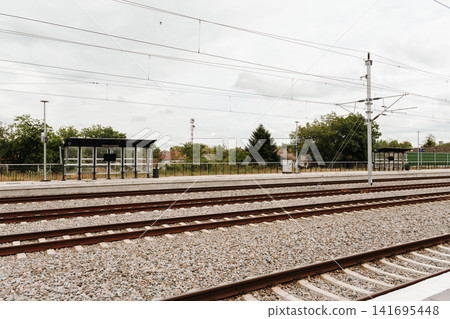 Railway station with multiple tracks and overhead electric lines under cloudy sky. Concept of transport infrastructure mobility and regional travel Railway station with multiple tracks and overhead electric lines under cloudy sky. Concept of transport infrastructure mobility and regional travel 141695448
