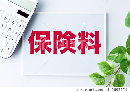 一塊寫著「保險費」字樣的白板和一個白色計算器。 一塊寫著「保險費」字樣的白板和一個白色計算器。 141695554