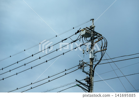 Utility poles and power lines, crossing the sky 141695885