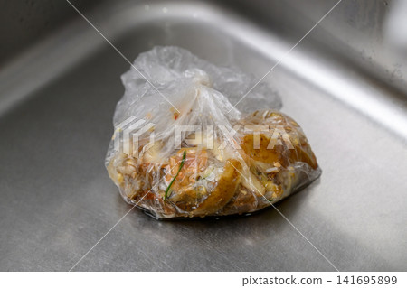 A plastic bag containing food waste placed in the sink. A plastic bag containing food waste placed in the sink. 141695899
