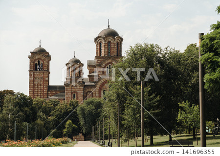 Saint Mark's Church rises above the trees in Tasmajdan Park in Belgrade, Serbia. Historic Orthodox architecture surrounded by lush greenery in a peaceful urban setting Saint Mark's Church rises above the trees in Tasmajdan Park in Belgrade, Serbia. Historic Orthodox architecture surrounded by lush greenery in a peaceful urban setting 141696355