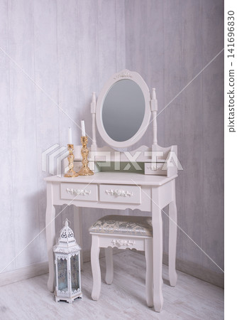 Elegant dressing table with a mirror, ottoman, candlesticks, and a lantern in a cozy room interior. Elegant dressing table with a mirror, ottoman, candlesticks, and a lantern in a cozy room interior. 141696830