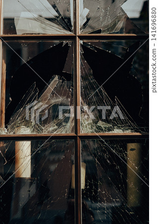 Broken window with shattered glass and sharp intricate cracks. Damaged building, vandalism, burglary, destruction, security breach and property damage Broken window with shattered glass and sharp intricate cracks. Damaged building, vandalism, burglary, destruction, security breach and property damage 141696880