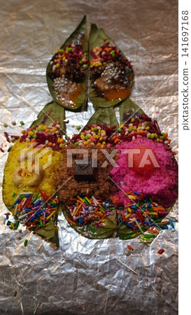 Decorative paan with coconut, chocolate, and sprinkles on silver background, fusion dessert concept Decorative paan with coconut, chocolate, and sprinkles on silver background, fusion dessert concept 141697168