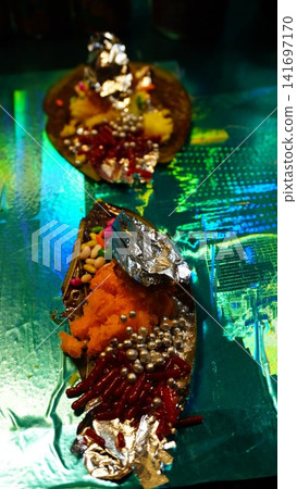 Ornate paan with candies and silver pearls on shimmering green surface, luxury dessert concept Ornate paan with candies and silver pearls on shimmering green surface, luxury dessert concept 141697170
