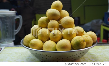Fresh lemons piled in metal colander at vibrant market stall, fresh produce concept Fresh lemons piled in metal colander at vibrant market stall, fresh produce concept 141697178
