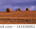 A tractor running through a wheat field 141698862