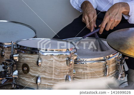 Drummer using a wire brush and stick on the snare of an acoustic drum kit 141699026