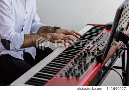 Keyboardist playing an electronic stage keyboard in a casual music session Keyboardist playing an electronic stage keyboard in a casual music session 141699027