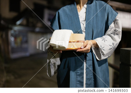 A woman in a yukata carrying a wooden bucket A woman in a yukata carrying a wooden bucket 141699303