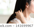 一位身穿蕾絲洋裝的女子，用手輕撫著自己的頭髮。 141699967