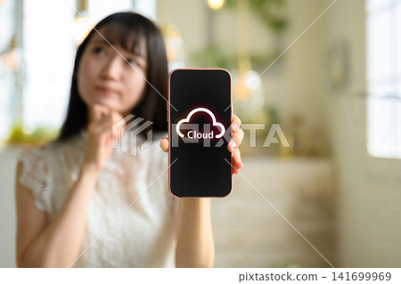 一名女子使用智慧型手機操作雲端服務。 一名女子使用智慧型手機操作雲端服務。 141699969