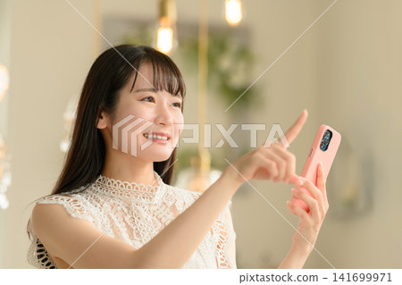 一個微笑的女人指著她的智能手機 一個微笑的女人指著她的智能手機 141699971