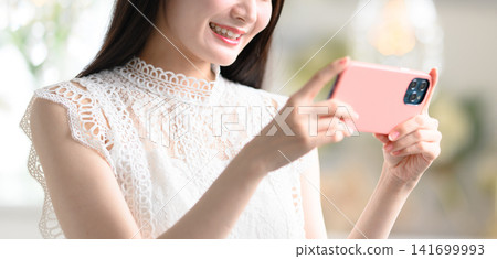 A woman holding her smartphone horizontally. A woman holding her smartphone horizontally. 141699993