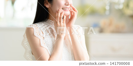 一位女士面帶微笑地撫摸著自己的臉頰。 141700008