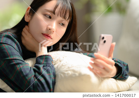 A young woman watching a smartphone A young woman watching a smartphone 141700017