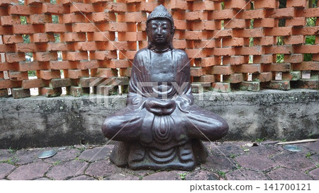 Serene Meditating Buddha Statue Against Textured Brick Wall Serene Meditating Buddha Statue Against Textured Brick Wall 141700121