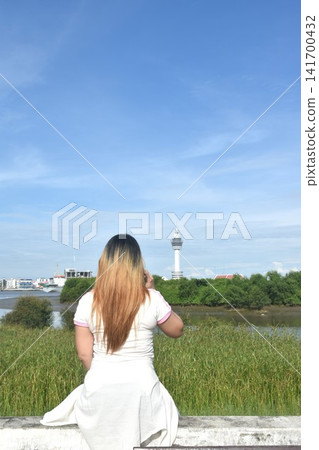 woman using mobile phone on Samut Prakan city town skyscraper view in Thailand woman using mobile phone on Samut Prakan city town skyscraper view in Thailand 141700432