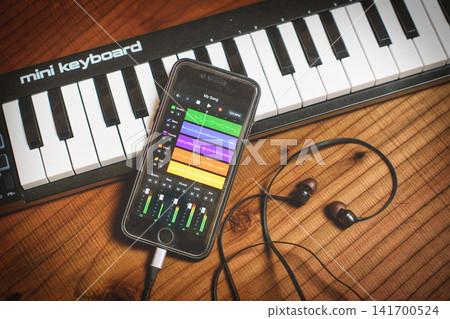 Smartphone Music Production App with Mini Keyboard and Earphones on Table Smartphone Music Production App with Mini Keyboard and Earphones on Table 141700524