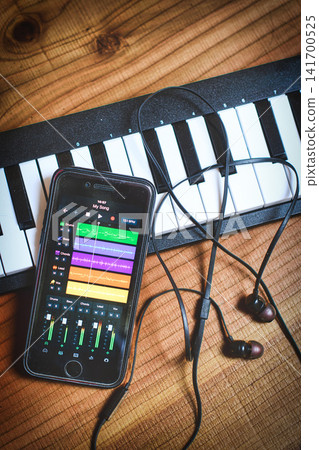 Smartphone with music app and headphones on keyboard against wooden background Smartphone with music app and headphones on keyboard against wooden background 141700525