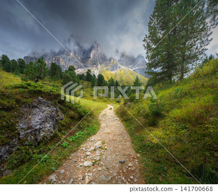 Hiking dirt path leading to mountain peaks in low clouds Hiking dirt path leading to mountain peaks in low clouds 141700668