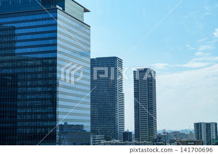 The modern cityscape of high-rise office buildings and tower apartments in Osaka's Umeda district stands out against the blue sky. The modern cityscape of high-rise office buildings and tower apartments in Osaka's Umeda district stands out against the blue sky. 141700696