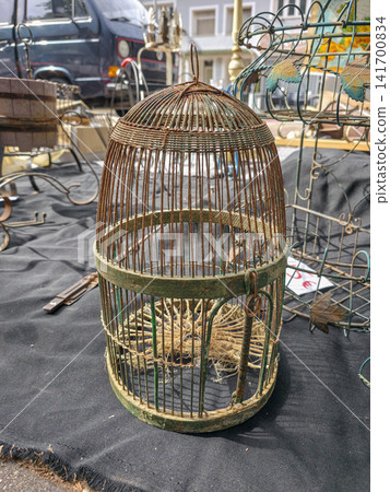 Xalo, Spain - June 20, 2026.Vintage rusted wire birdcage for sale at outdoor flea market among various antiques and items 141700834