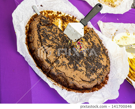 Homemade chocolate cake with sprinkles and flower petals served on baking paper at a gathering Homemade chocolate cake with sprinkles and flower petals served on baking paper at a gathering 141700846