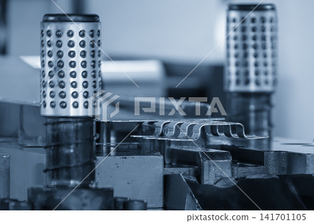 Metal parts mass production process from progressive die stamping in blue tone lighting. 141701105