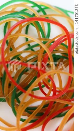 close up of a tangled pile of red, green, yellow and tan rubber bands on a clean white table surface with copy space close up of a tangled pile of red, green, yellow and tan rubber bands on a clean white table surface with copy space 141701258