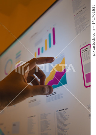 A business person's hands operating bar graphs and line graphs on a touch panel. 141701633