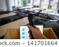 A hand holding a microphone and a laptop with presentation materials. 141701664
