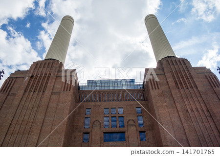 Battersea Power Station, with its renovated large white chimney, stands under a blue sky and bright sunshine – a new London tourist attraction. Battersea Power Station, with its renovated large white chimney, stands under a blue sky and bright sunshine – a new London tourist attraction. 141701765