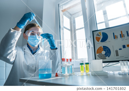 A laboratory scientist wearing safety gear uses a pipette to transfer liquid while analyzing data on a computer. The scene highlights innovation, research, and advanced laboratory technology A laboratory scientist wearing safety gear uses a pipette to transfer liquid while analyzing data on a computer. The scene highlights innovation, research, and advanced laboratory technology 141701802