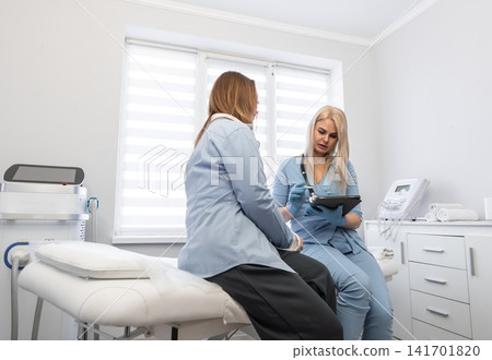 Woman physician provides medical advice to patient, utilizing digital technology for efficient healthcare service. Modern clinic setting emphasizes trust, communication, advanced patient care Woman physician provides medical advice to patient, utilizing digital technology for efficient healthcare service. Modern clinic setting emphasizes trust, communication, advanced patient care 141701820