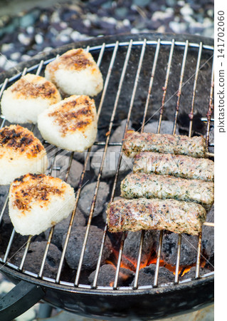 Sausages and grilled rice balls lined up on a barbecue grill. Sausages and grilled rice balls lined up on a barbecue grill. 141702060