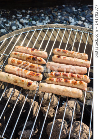 Sausages lined up on a barbecue grill for a barbecue dinner at home. Sausages lined up on a barbecue grill for a barbecue dinner at home. 141702377