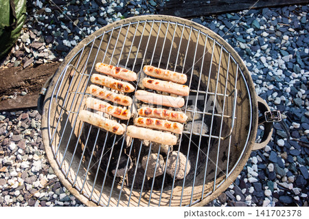 Sausages lined up on a barbecue grill for a barbecue dinner at home. Sausages lined up on a barbecue grill for a barbecue dinner at home. 141702378