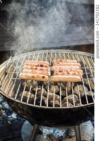 Sausages lined up on a barbecue grill for a barbecue dinner at home. Sausages lined up on a barbecue grill for a barbecue dinner at home. 141702382
