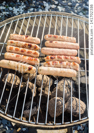 Sausages lined up on a barbecue grill for a barbecue dinner at home. Sausages lined up on a barbecue grill for a barbecue dinner at home. 141702386