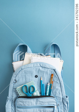 Light blue backpack with notebooks pencils scissors and brushes on a blue background 141702396